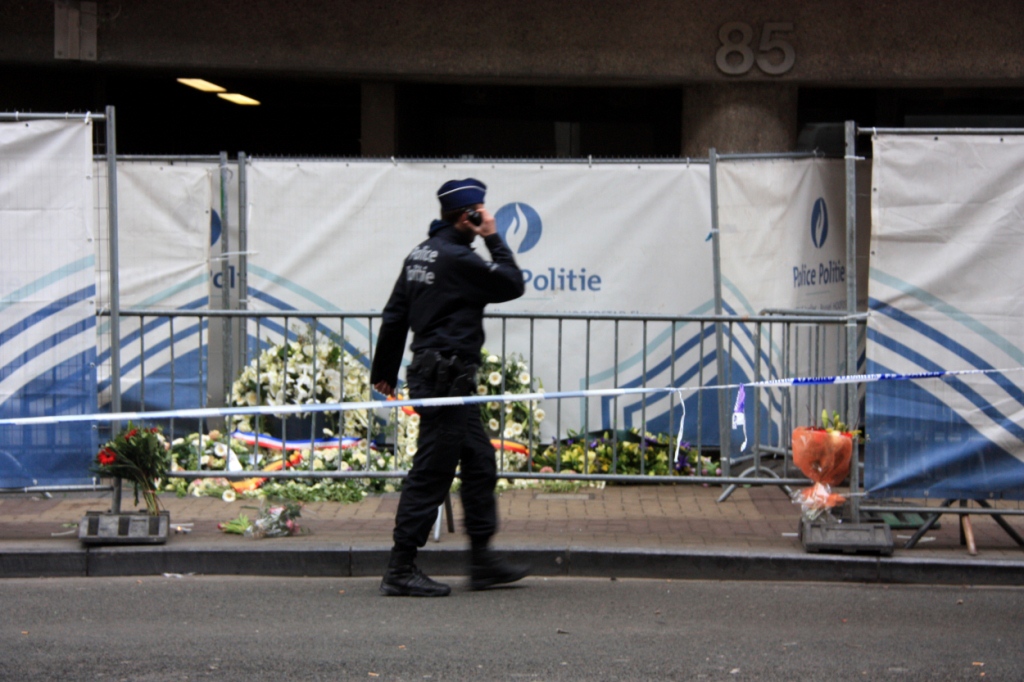 Un policia passa davant de les ofrenes florals a l'estació de metro de Maalbeek, a Brussel·les / Foto: ACN