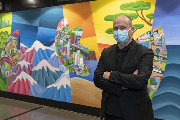 L'artista Philip Stanton posa davant de la seva creació, el mural 'Els colors de l'agraïment' / Foto: Miguel Ángel Cuartero (TMB)