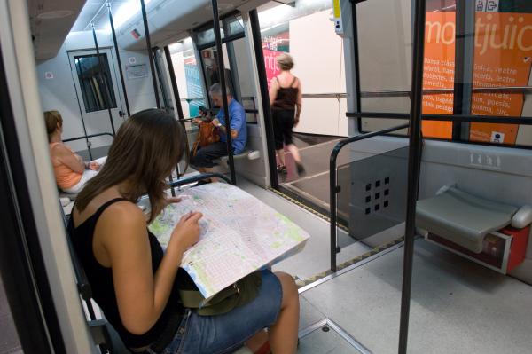 Una usuària consultant un plànol de bus asseguda dins el funicular de Montjuïc.